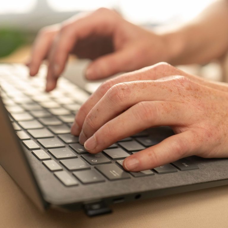 Christina Winter | kreative Unterstützung für Marketing-Solisten Hände tippen auf einer dunklen Tastatur, im Hintergrund unscharf.